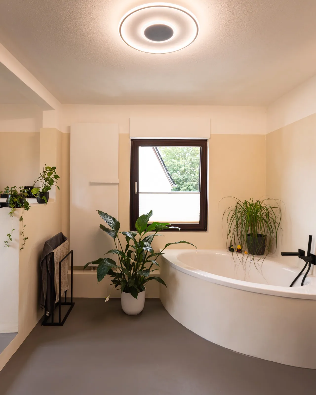 Fugenlos gestaltetes Badezimmer mit Badewanne, Waschtisch und schwarzen Armaturen