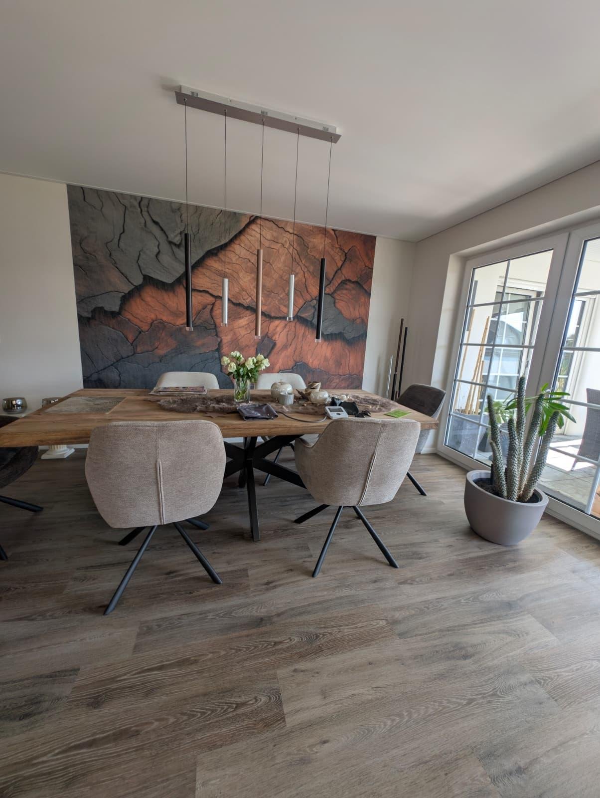 Esszimmer mit Holzdielenboden und großformatiger Mustertapete in Terrakotta- und Grautönen
