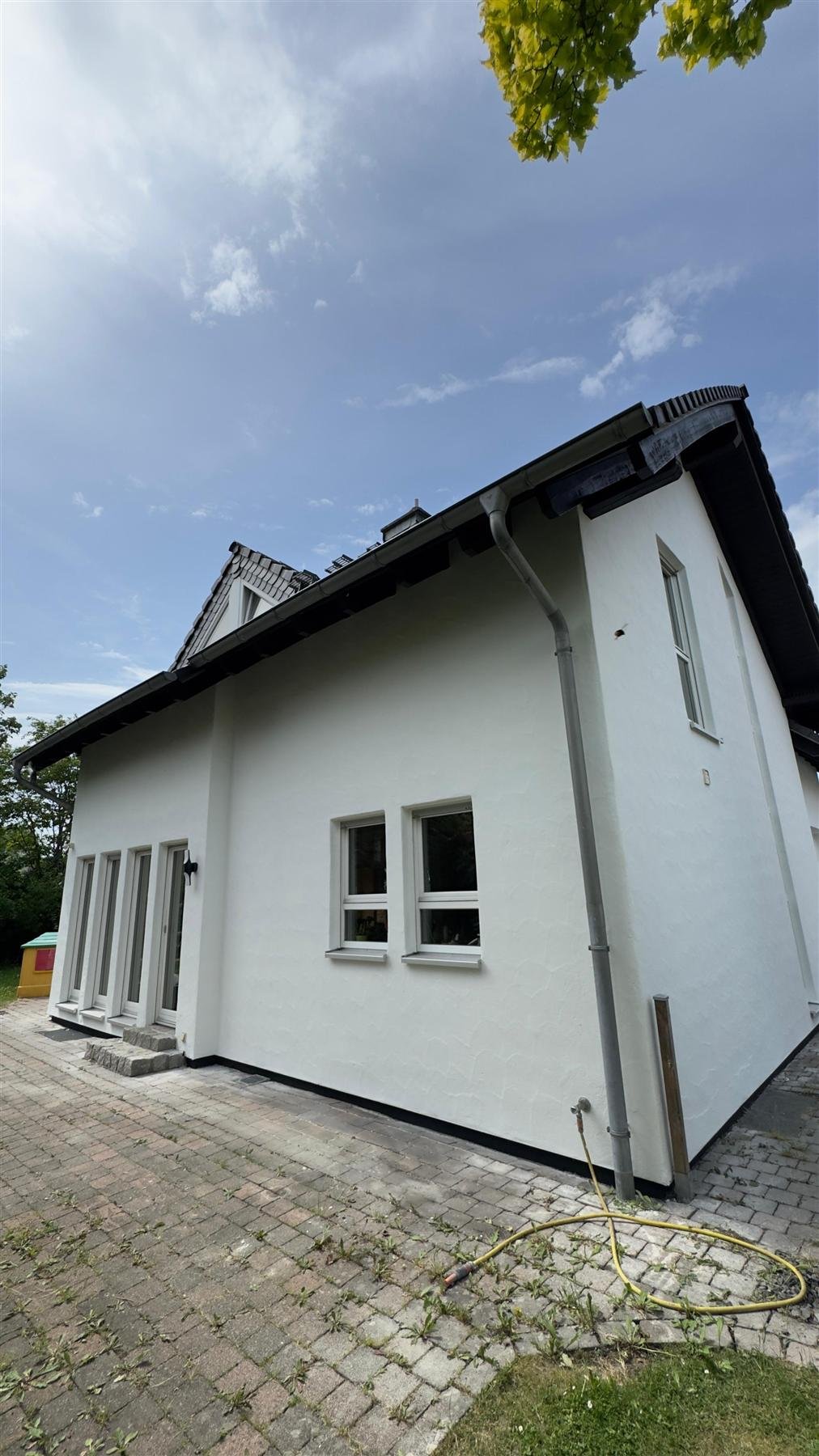 Weiß verputztes Einfamilienhaus mit Garage nach der Fassadensanierung