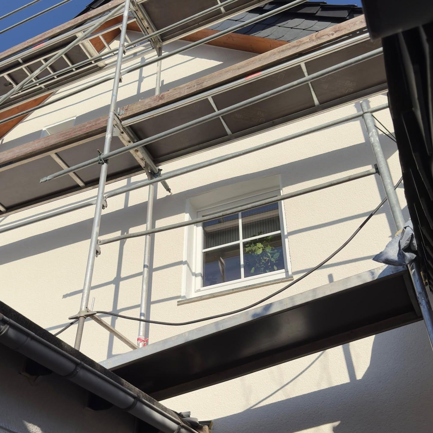 Neu verputzte helle Fassade im Detail, aufgenommen durch das Baugerüst