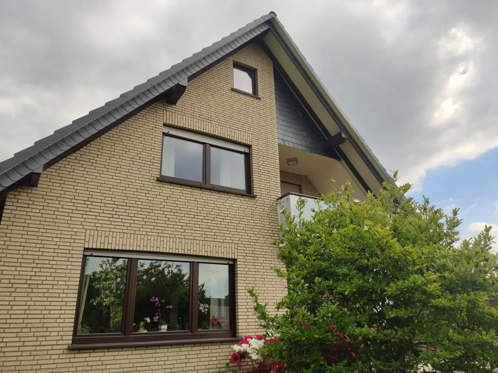 Backsteinfassade eines Giebelhauses mit gepflegtem Vorgarten