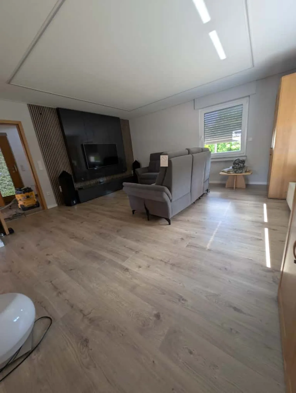 Wohnzimmer mit Holzlamellenwand und Fernseher