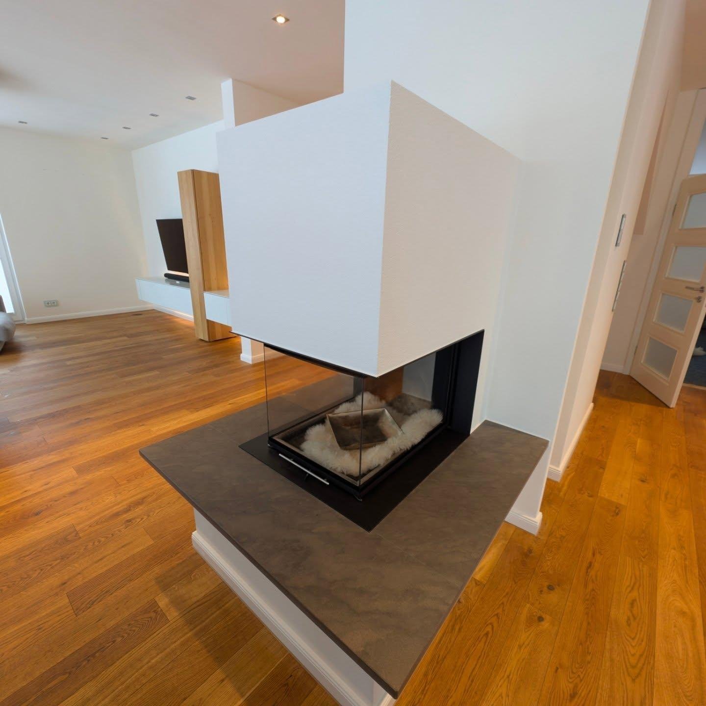 Modernes Wohnzimmer mit freistehendem weißem Kamin und Holzdielenboden