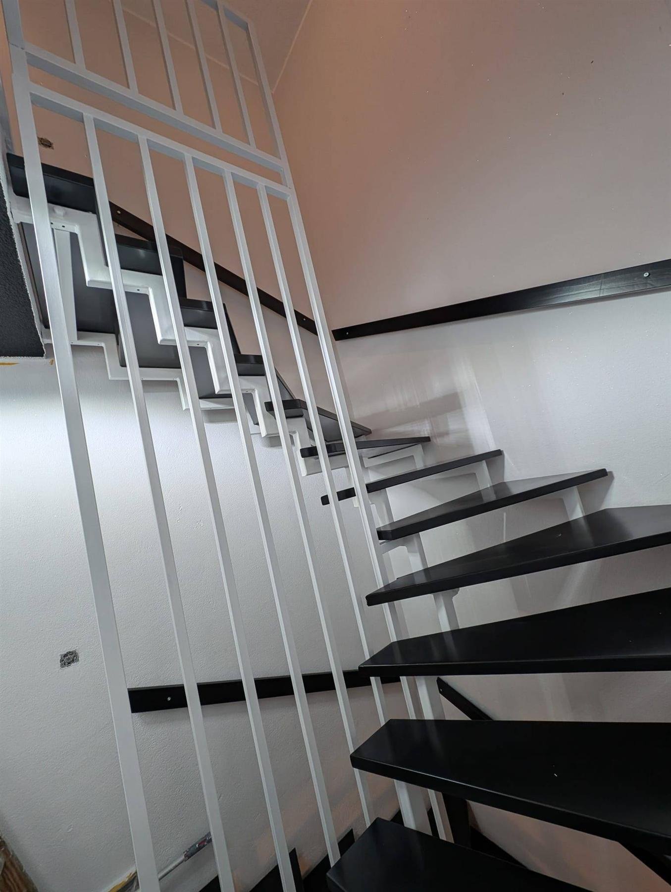 Moderne freitragende Treppe mit schwarz lackierten Stufen und weißem Geländer