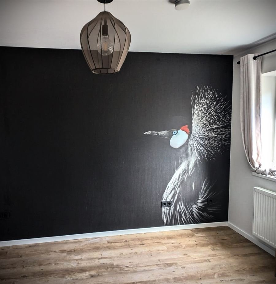 Dunkle Wand mit großformatigem Kranich-Wandbild und Pendelleuchte