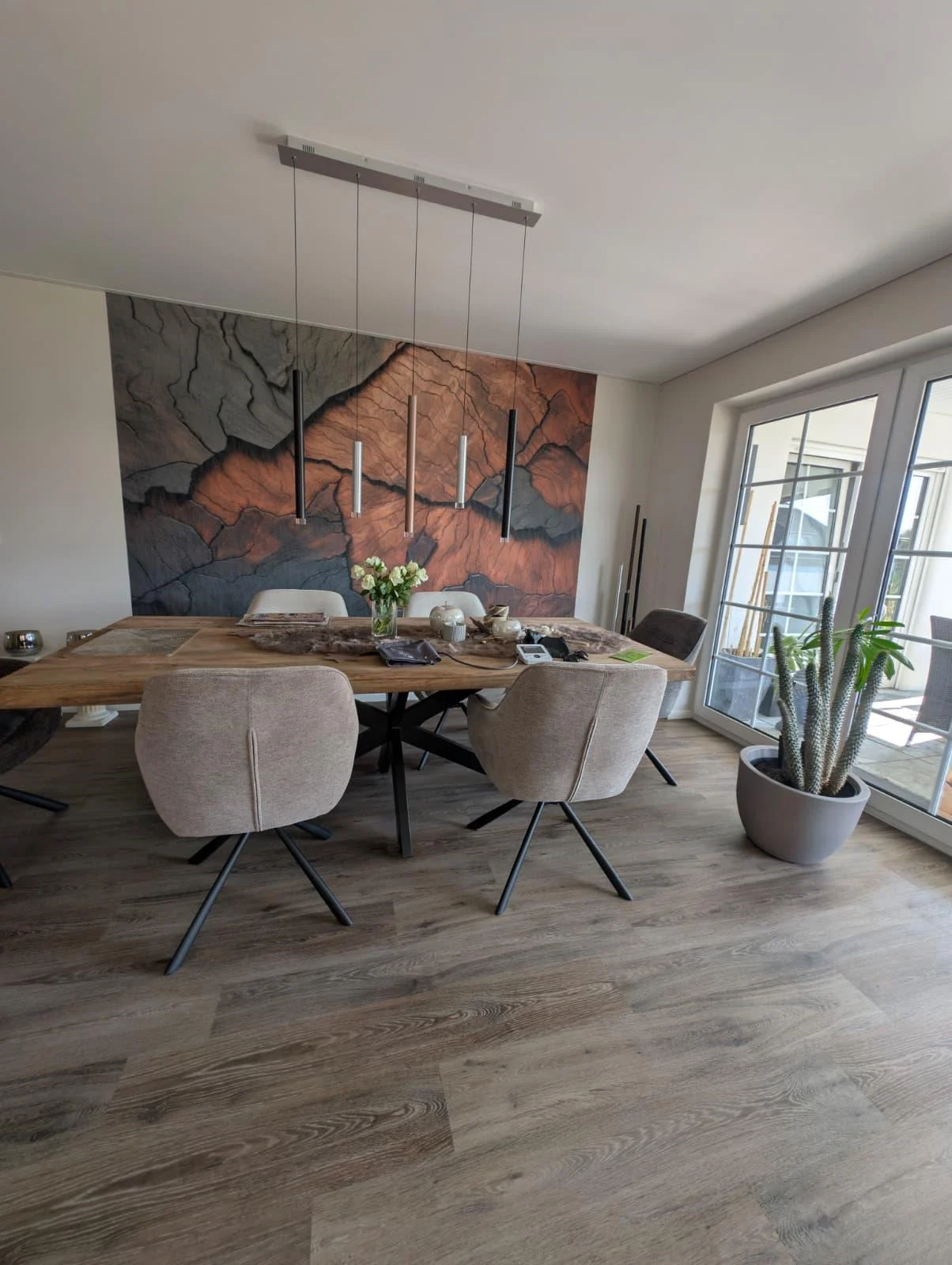 Esszimmer mit Holzdielenboden und großformatiger Mustertapete in Terrakotta- und Grautönen
