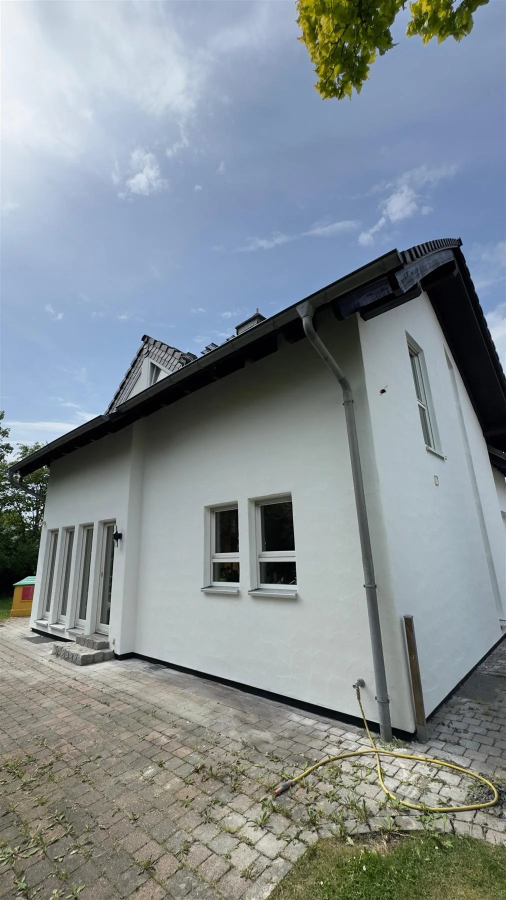 Weiß verputztes Einfamilienhaus mit Garage nach der Fassadensanierung