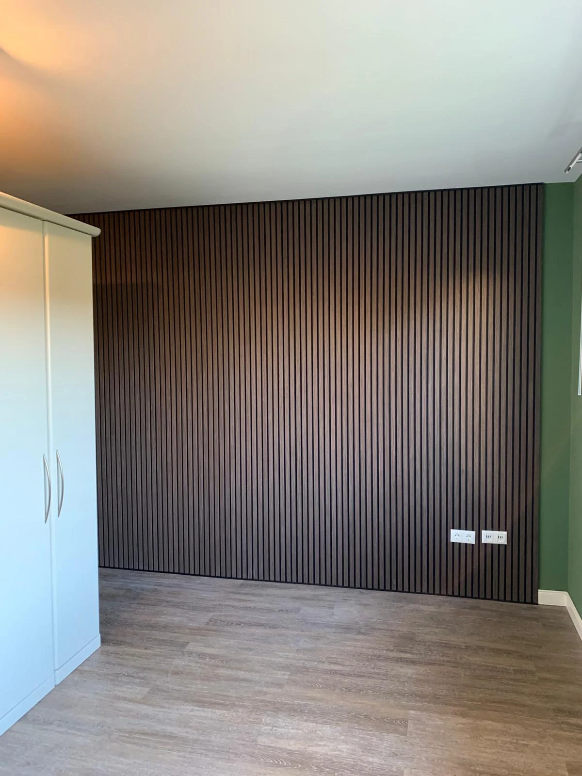 Schlafzimmer mit grüner Wandfarbe und Akustik-Lamellenwand aus Holz
